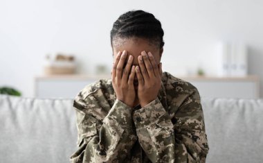 Zihinsel çöküntü. Elleriyle yüzünü kapatan depresif siyah asker kadın, kamuflaj üniformalı Afro-Amerikan kadın, koltukta oturuyor ve ağlıyor, travma sonrası stres bozukluğu yaşıyor, boşluğu kopyalıyor.