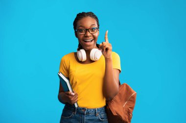 Harika bir fikir. Heyecanlı Siyahi Öğrenci Kız Parmak Kalkmış Mavi Stüdyo Arkaplanında Duran Eureka Anını Gösteriyor.