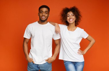 Serin millennials. Neşeli siyah adam ve kız portakal studio arka plan üzerinde poz