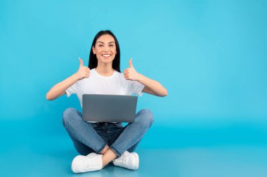 Harika bir site. Dizüstü bilgisayar kullanan tatmin olmuş ergen parmak hareketleriyle turkuaz zeminde oturuyor. Stüdyo Çekimi