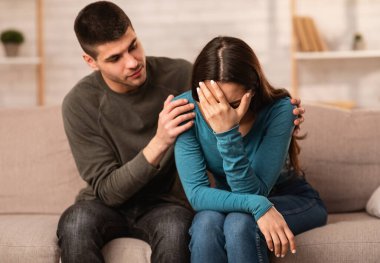 Şefkat kavramı. Adam, kederli arkadaşını teselli ediyor ve teselli ediyor. Onu kanepede otururken kucaklıyor.