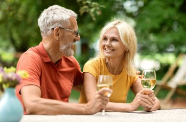 Evli, kıdemli çiftin dışarıda şarap içerken, mutlu, olgun eşlerin bahçede otururken, dışarıda piknik yaparken, birbirlerine bakıp gülümserken, yıldönümlerini kutlarken.