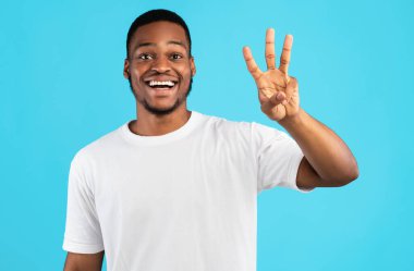 Üç Numara. Afro-Amerikalı Adam Mavi Arkaplanda Üç Parmak Sayıyor. Stüdyo Arkaplanı