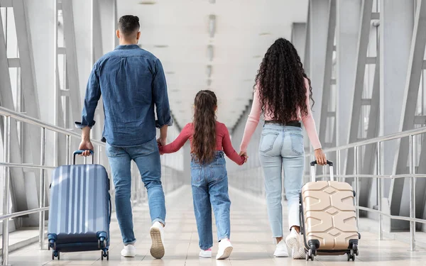 Havalimanında birlikte yürürken aile fotoğrafı, tanınmayan ebeveynler ve küçük kız el ele tutuşurken bavulları uçuş kapısına giderken görüntülendi.