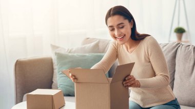 Müşteri, büyük alımlardan memnun kalarak iyi bir paket açık karton kutu alıyor. Mutlu Müslüman tüketici paketini boşalt, oturma odasının iç kısımlarına postayla teslimat yapılmasından mutlu bir şekilde içine bak.