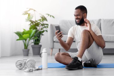 Neşeli genç siyahi adam halterler ve su şişesiyle odanın içinde yerde oturup el sallayarak webcam 'e sesleniyor. Toplantı, canlı yayın, evdeki iletişim ve uygulama