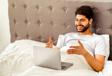 Mutlu Arap adamın dizüstü bilgisayarında görüntülü araması, hafta sonu evde oturup ailesiyle uzaktan konuşması, bilgisayar ekranına el kol hareketi yapması. Uzak iletişim konsepti