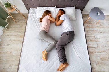 Sevecen, çok ırklı bir çiftin yatakta yan yana yatması. Gencecik, çokuluslu aile uykuları, yatak odasında tembel bir sabah.