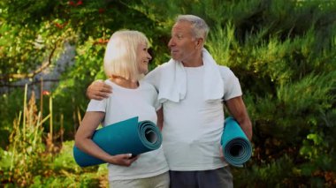 İki son sınıf öğrencisi, canlı bir bahçede yoga minderlerini tutarken gülümseyip birbirlerine bağlanıyorlar. Neşeli atmosfer, sakin bir ortamda zindelik ve sağlığa olan ortak tutkularını vurguluyor..