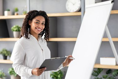 Evde çalış ve çalış, sosyal uzaklık, eğitim ve kurslar çevrimiçi. Video blogu çekiyorum. Gülümseyen sevimli Afro-Amerikan bayan tahtada yazıyor, tableti tutuyor, evde öğretmenlik yapıyor, boş yer var.