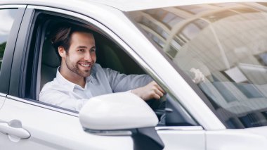 Şehir trafiği, harika bir ruh hali, insanlar ve ulaşım. Yeni rahat otomobil. Neşeli Avrupalı beyaz gömlekli çekici adam direksiyon başında oturuyor, araba kabininde, ofise gidiyor, boş yer var.