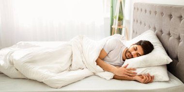 Yatma vakti. Bin yıllık Arap adam uykuda, yatak odasındaki beyaz rahat yatakta dinleniyor, kopyalama uzayı. Dinlen, rahatla, hafta sonları evde uyu..