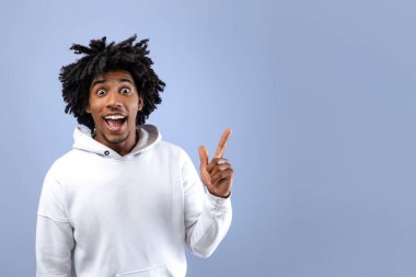 Çılgın siyahi genç adam AHA anı yaşıyor, yaratıcı bir fikri var, Violet stüdyosunun arka planına bakıyor, kopyalama alanı. Çekici Afro-Amerikan genci Eureka 'yı işaret ediyor.