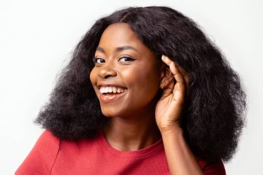 Kulak misafiri olmaya çalışan meraklı, neşeli, siyah bir kadın, taze dedikodularla ilgilenen, beyaz arka planda izole edilmiş, yakın planda poz veren genç, Afro-Amerikan kadın.