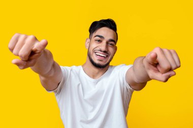 Hey sen! Karizmatik, yakışıklı, sakallı, ortadoğu çocuğu sarı stüdyo arka planında poz veriyor, kameraya bakıyor, iki eliyle işaret ediyor, yakın plan portresi, panorama