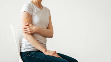 Bağışıklık sistemi, anti virüs kampanyası ve koronavirüs önleme. Yetişkin kadın hasta aşıdan sonra omzunda yara bandı, gri arka planda izolasyon, boş alan, panorama, kesilmiş