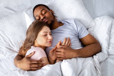 Irklar arası sevgi dolu bir çiftin yatakta uyuyup birbirlerini kucaklamasının en iyi görüntüsü. Afro-Amerikalı bir adam dinlenirken beyaz karısına sarılıyor. Çok ırklı ilişkiler ve evlilik kavramı