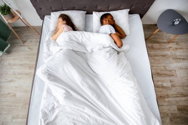 Irklar arası genç çiftin evlerinde sırt sırta uyumalarının en iyi görüntüsü. Siyahi adamla Kafkasyalı kız arkadaşının ilişki sorunları olduğunu gösteren bir fotoğraf. Aile ayrılığı ya da boşanma kavramı