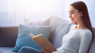 Covid-19 tecrit, boş zamanlarında edebiyat, sessizlik ve entelektüel hobi. Genç, güzel Müslüman bir kadın kanepeye uzanıyor ve oturma odasındaki en sevdiği kitabı, defteri ya da günlüğü okuyor.