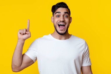Duygusal, genç, yakışıklı Arap adam parmağını kaldırıyor ve çığlık atıyor, sarı stüdyo arka planında 