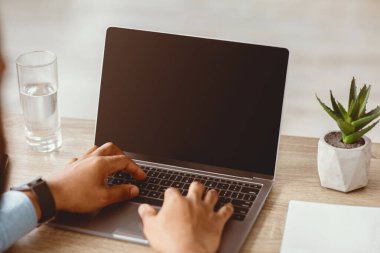 Genç Afro-Amerikalı adam ofisin iç kısımlarında boş ekranla bilgisayarda yazı yazıyor, kapat. Covid-19 karantina, iş ve iş, içeride sohbet. Web sitesi, reklam ve aygıt üzerine teklif