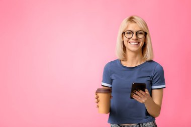 Modern öğrenci elinde kahve ile bej arka planda akıllı telefon kullanıyor ve stüdyo çekimi var. Dersten sonra kahve molası veren bir bayan, cep telefonu kullanıyor.