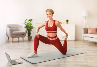 Antrenmandan önce ısınıyorum. Oturma odasında gülümseyen, formda bir kadın antrenmanı yapan, güzel kadın bacaklarını esneten, Mat 'te egzersiz yaptıktan sonra serinleyen, serbest alan...