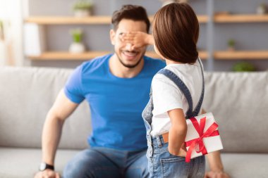 Arkaya bakan sevgi dolu kız, arkasında paketlenmiş hediye kutusu tutuyor ve saklıyor. Heyecanlı babaya sürpriz yapıyor, gözlerini kapatıyor. Babalar günü ya da doğum günü olan genç adamı selamlıyor.