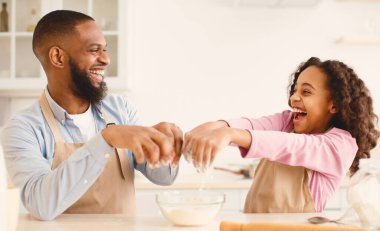 Birlikte vakit geçirmek. Gülen Afrikalı Amerikalı adam ve kızının portresi, hamur yapmak, un, baba ve kız pizza, kurabiye, pasta veya ekmek hazırlarken mutfakta eğlenmek ve gülümsemek.