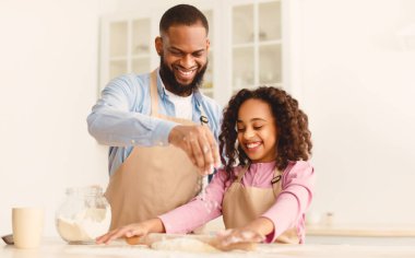 Birlikte vakit geçirmek. Gülümseyen Kara Sakallı Adam ve Şirin Kıvırcık Çocuk Mutfakta Pasta Pişiriyorlar, Kızları Ahşap masa üzerinde gübre örüyorlar, Rolling Pin kullanıyorlar, Baba un ekliyorlar, bedava kopyalama alanı