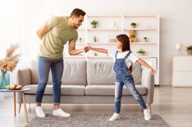 Babalar Günün kutlu olsun. Genç, gülümseyen bir babanın, tatlı küçük kızıyla evde dans etmesi, elini tutması, eğlenmesi ve birlikte boş zaman geçirmesi, modern iç mekan.