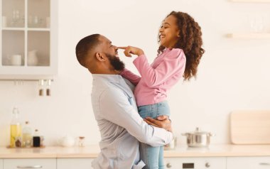 Sevgi dolu bir aile. Şirin kıvırcık kız ve babası mutfakta yemek pişirirken, sağlıklı salata hazırlarken, Baba Burnu 'na Dokunan Kız' ı kucaklarken,