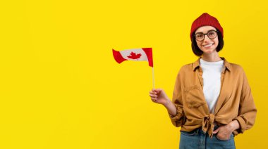 Yurtdışında eğitim, Kanada 'da eğitim, göç kavramı. Pozitif kadın öğrenci el ele vererek poz veriyor sarı stüdyo arka planı, kopyalama alanı