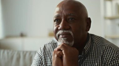 Yaşlı bir Afrikalı Amerikalı adam evinde rahatça otururken düşünceli bir şekilde yansıtır. Sıcak atmosfer, 60 'lı yaşlarının bilgeliğini kucaklayan barışçıl bir yaşam tarzı olduğunu gösteriyor..