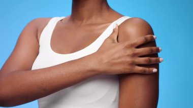 Bin yıllık Afro-Amerikan bir kadın sağ elini sol omzuna koyup güvenini gösteriyor. Parlak mavi arkaplan ana canlı bir dokunuş katıyor..