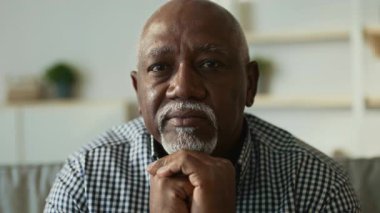 Yaşlı bir Afrikalı Amerikalı adam rahat bir ev ortamında oturur, dalgın dalgın bakar. Düşünceli ifadesi, onun hayat tecrübesinden derin bir yansıma ve bilgeliği olduğunu gösteriyor..