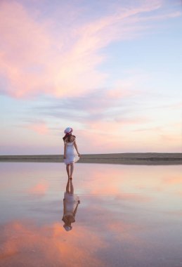 Bir kız bulutların bir yansıması ile su içinde yürür.