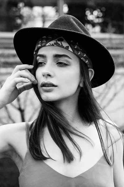 スタイリッシュな若い女性おしゃれな帽子をかぶっていると屋外でポーズの黒と白の写真 — ストック写真