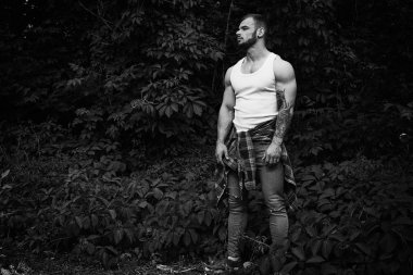 Siyah ve beyaz fotoğraf yakışıklı genç erkek adam açık havada yaz ormanda poz