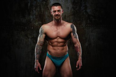 Gömleksiz kaslı genç adam grunge duvar arka planı poz 