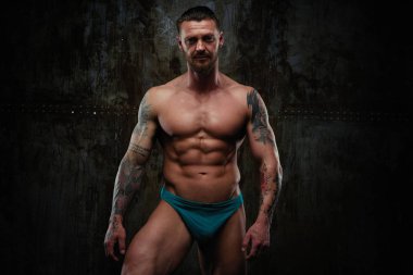 Gömleksiz kaslı genç adam grunge duvar arka planı poz 