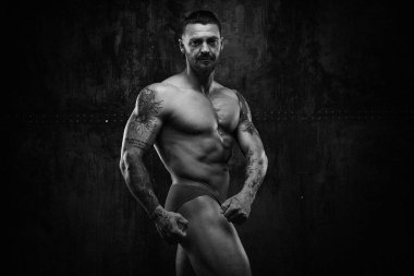 Siyah ve beyaz fotoğraf gömleksiz kaslı genç adamın grunge duvar arka planı poz 