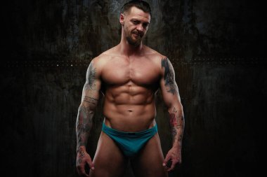 Gömleksiz kaslı genç adam grunge duvar arka planı poz 