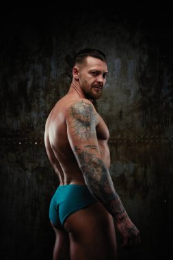 Gömleksiz kaslı genç adam grunge duvar arka planı poz 