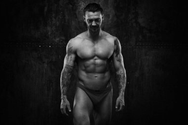 Siyah ve beyaz fotoğraf gömleksiz kaslı genç adamın grunge duvar arka planı poz 
