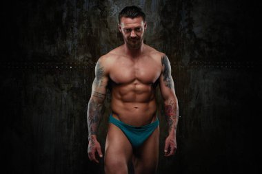 Gömleksiz kaslı genç adam grunge duvar arka planı poz 