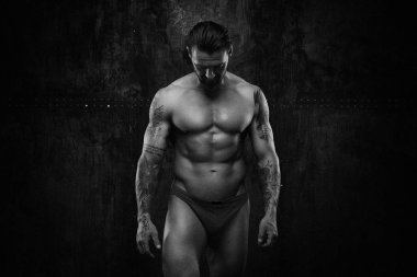 Siyah ve beyaz fotoğraf gömleksiz kaslı genç adamın grunge duvar arka planı poz 