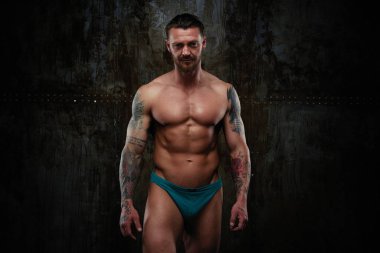 Gömleksiz kaslı genç adam grunge duvar arka planı poz 