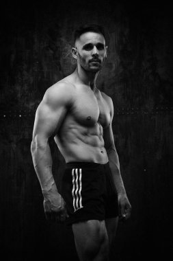Siyah ve beyaz fotoğraf gömleksiz kaslı genç adamın grunge duvar arka planı poz 