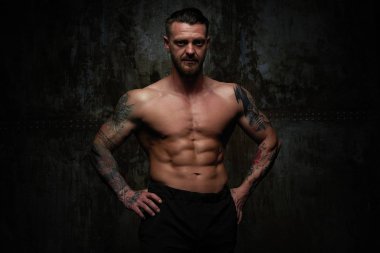 Gömleksiz kaslı genç adam grunge duvar arka planı poz 